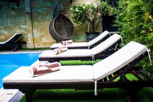 a group of lounge chairs sitting next to a pool at Bali 85 Beach Inn in Padangbai