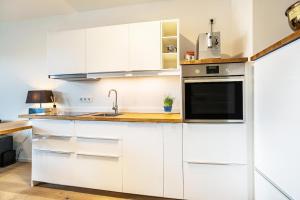 a kitchen with white cabinets and a sink at Weserloft 16 in Bremen