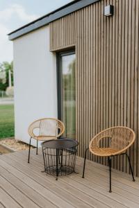 zwei Stühle und zwei Tische auf einer Holzterrasse in der Unterkunft Gyopár Lodge - Gyopárosfürdő in Orosháza