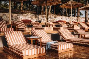 una fila de sillas y sombrillas en un patio en Cook's Club Ialysos Rhodes, en Ialisos