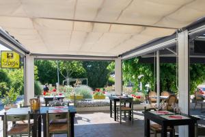 un patio con mesas y sillas bajo un pabellón en Hôtel Restaurant Le Clos Charmant, en Vallon-Pont-dʼArc