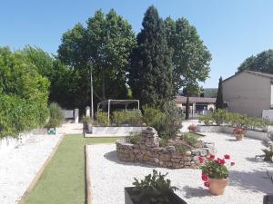 un jardín con una pared de piedra, plantas y flores en Hôtel Restaurant Le Clos Charmant, en Vallon-Pont-dʼArc