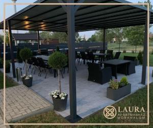 d'une terrasse avec des tables et des chaises sous un auvent. dans l'établissement Laura Apartmanház, à Mórahalom