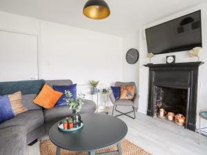 a living room with a couch and a table and a fireplace at Bwthyn Siliwen Old Bath House in Bangor