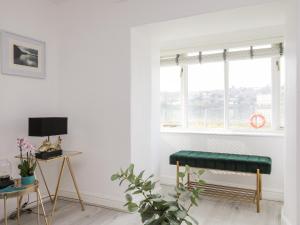 a living room with a green bench in front of a window at Bwthyn Siliwen Old Bath House in Bangor