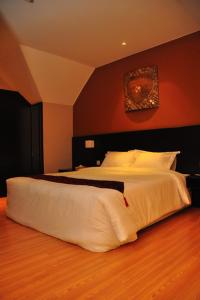 a bedroom with a large white bed with a red wall at Tat Place Hotel in Kuala Belait