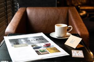 una mesa con una taza de café y un periódico en HOTEL THE FLAG Shinsaibashi, en Osaka