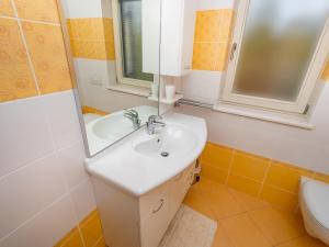 La salle de bains est pourvue d'un lavabo, d'un miroir et de toilettes. dans l'établissement APARTMANI KRAJ, à Mošćenička Draga