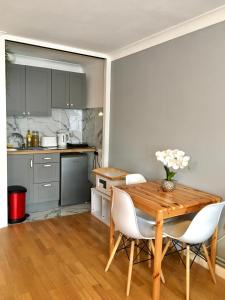 - une cuisine avec une table en bois et des chaises blanches dans l'établissement Lovely Studio Room in the heart of Kingston upon Thames, à Kingston upon Thames