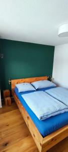 een slaapkamer met een houten bed met een groene muur bij Casa Basilea in Valbella