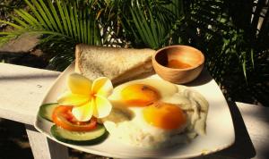 um prato de ovos e pão com uma flor em The Pancor Jungle Resort em Nusa Penida