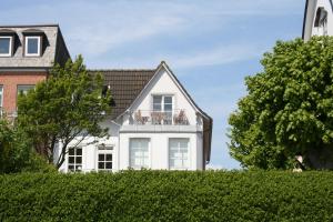 une maison blanche avec un balcon au-dessus d'une haie dans l'établissement Sandwallkoje, à Wyk auf Föhr