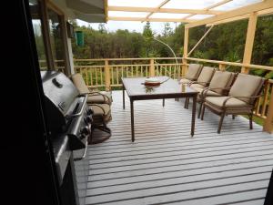 eine abgeschirmte Veranda mit einem Tisch und Stühlen auf einer Terrasse in der Unterkunft Fern Forest Getaway in Volcano