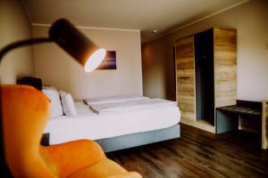 a bedroom with a bed and a chair and a lamp at Romantik Hotel Schmiedegasthaus Gehrke in Bad Nenndorf