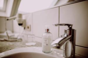 a bottle of soap sitting on top of a bathroom sink at Romantik Hotel Schmiedegasthaus Gehrke in Bad Nenndorf