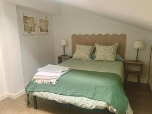 a bedroom with a bed with a green comforter at Precioso apartamento castro Urdiales in Castro-Urdiales