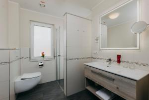 een badkamer met een wastafel, een toilet en een spiegel bij Hotel Alter Muschelsaal in Büsum