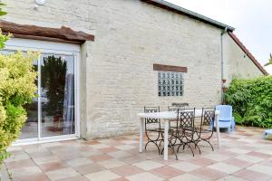 un patio con mesa y sillas y un edificio en Isida, Maison spacieuse avec terrasse et stationnement, en Caen