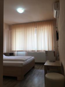 - une chambre avec un lit et une fenêtre avec des rideaux dans l'établissement Cazare Hofmann, à Arad