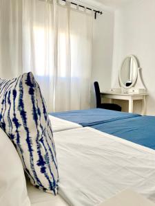 un letto con una coperta blu e bianca e uno specchio di Pirata Milfontes Guest House a Vila Nova de Milfontes