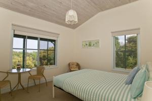 ein Schlafzimmer mit einem Bett, einem Tisch und zwei Fenstern in der Unterkunft Bennetts Beach House in Apollo Bay