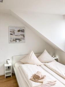 un letto con lenzuola bianche e un cappello sopra di Seebox Appartment 6 a Norderney