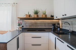 una cocina con armarios blancos y encimeras negras en Landhaus Theresia, en Maria Alm am Steinernen Meer