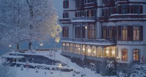 een groot gebouw in de sneeuw met lichten aan bij Grandhotel Giessbach in Brienz