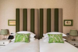 a bedroom with two beds and a green wall at Vmaison Brera Milano in Milan