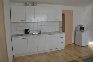 a white kitchen with white cabinets and a sink at apartmány LUHA in Luhačovice