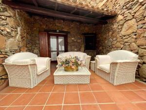 een patio met rieten stoelen en een tafel met bloemen bij SAN TEODORO PUNTA EST SPETTACOLARE QUADRILOCALE VISTA MARE in Capo Coda Cavallo