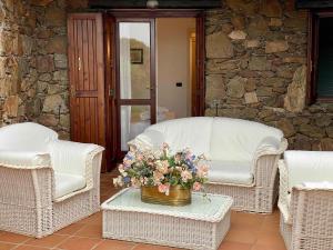 twee rieten stoelen en een vaas met bloemen op een tafel bij SAN TEODORO PUNTA EST SPETTACOLARE QUADRILOCALE VISTA MARE in Capo Coda Cavallo