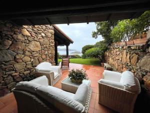 een patio met witte banken en een stenen muur bij SAN TEODORO PUNTA EST SPETTACOLARE QUADRILOCALE VISTA MARE in Capo Coda Cavallo