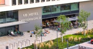 - une vue aérienne sur un bâtiment avec des personnes assises dans une cour dans l'établissement V8 HOTEL Motorworld Region Stuttgart, à Böblingen