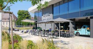 un groupe de tables et de chaises devant un bâtiment dans l'établissement V8 HOTEL Motorworld Region Stuttgart, à Böblingen