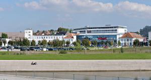 deux personnes assises sur un mur à côté d'une masse d'eau dans l'établissement V8 HOTEL Motorworld Region Stuttgart, à Böblingen