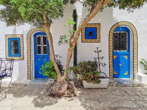 un albero davanti a un edificio con porte blu di Hôtel Bou Fares a Sidi Bou Saïd