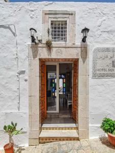 una porta per un edificio con tavolo e sedie di Hôtel Bou Fares a Sidi Bou Saïd