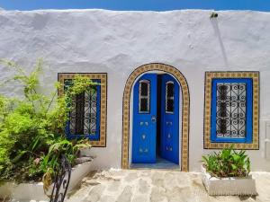 una porta blu e due finestre su un edificio bianco di Hôtel Bou Fares a Sidi Bou Saïd