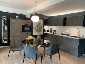 cocina y comedor con mesa de cristal y sillas en FeWo Prora - Designapartment Sir Henry, en Binz