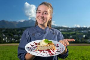 una mujer sosteniendo un pedazo de pastel en un plato en T3 Hotel Mira Val, en Flims