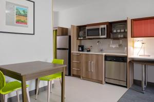 uma pequena cozinha com uma mesa e uma cozinha com um frigorífico em Home2 Suites By Hilton Baton Rouge Citiplace em Baton Rouge