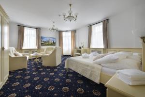 a hotel room with a large bed and chairs at Hotel Podhrad in Hluboká nad Vltavou