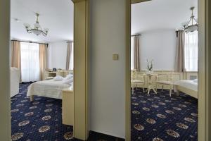 a hotel room with two beds and a table and chairs at Hotel Podhrad in Hluboká nad Vltavou