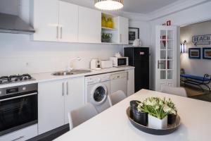 a kitchen with white cabinets and a table with plants at Casa "Vó Minda" - Nazaré - Alojamento Local in Nazaré