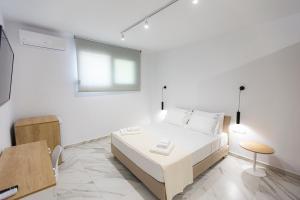 um quarto branco com uma cama e uma mesa em The Angeliki Boutique Hotel em Skala Rachoniou