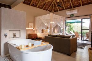 Moya Safari Lodge & Villa في هويدزبروت: غرفة معيشة مع حوض وغرفة نوم