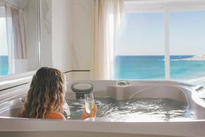 Una donna seduta in una vasca da bagno con un drink di Fistral Beach Hotel and Spa - Adults Only a Newquay