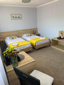 a room with two beds and a table with flowers at Hotel Alpex in Zabrze