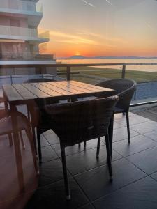 d'une table et de chaises en bois sur un balcon avec vue sur le coucher du soleil. dans l'établissement Hullám Apartman, à Balatonlelle